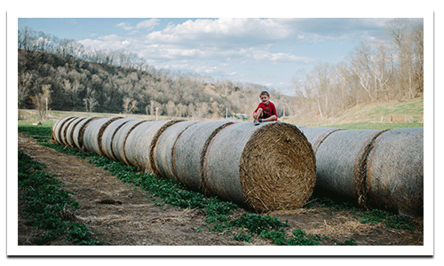 Boy sitting on hay bales in Cashton, WI